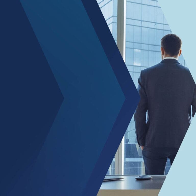 A businessman in a suit stands by a window, looking out at a city skyline.