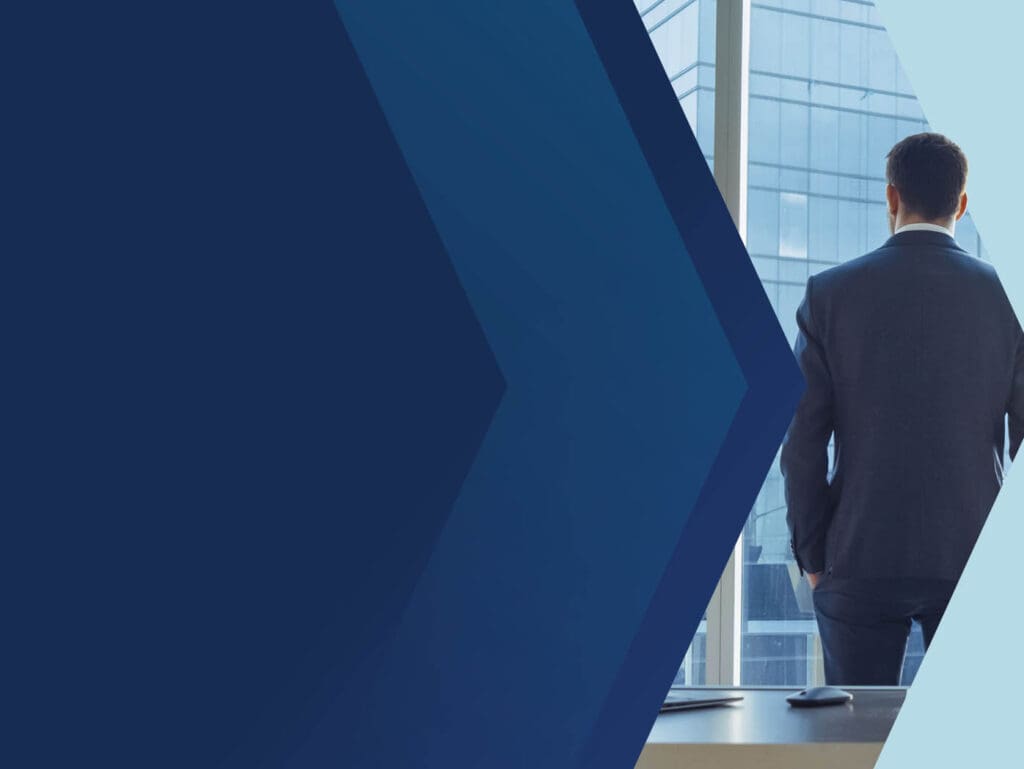 A businessman in a suit stands by a window, looking out at a city skyline.