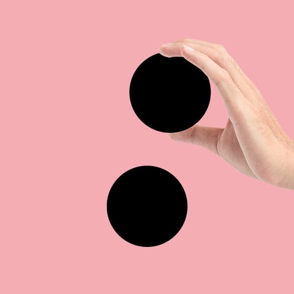 A hand holds a black circle over a second black circle on a pink background.