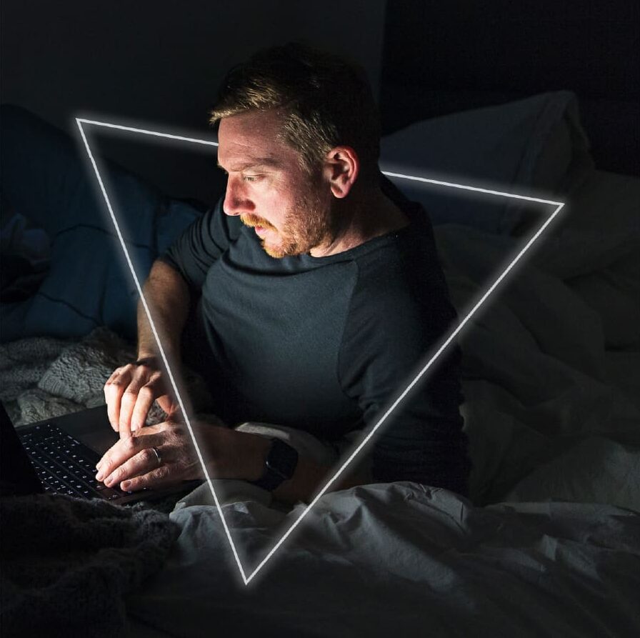 Man using laptop in bed at night with glowing triangular light frame overlay