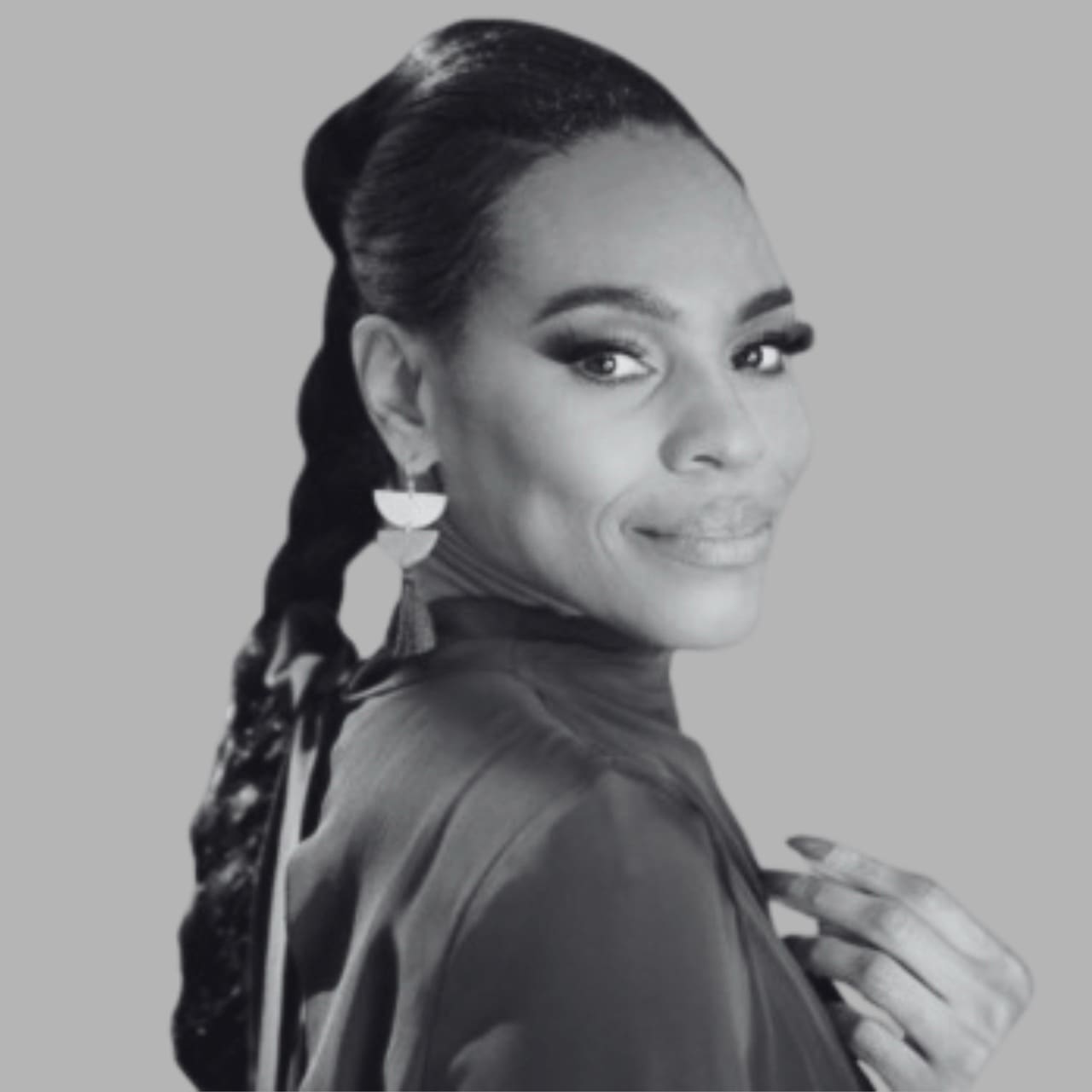 Black and white image of a woman with long hair, wearing earrings and a stylish top.